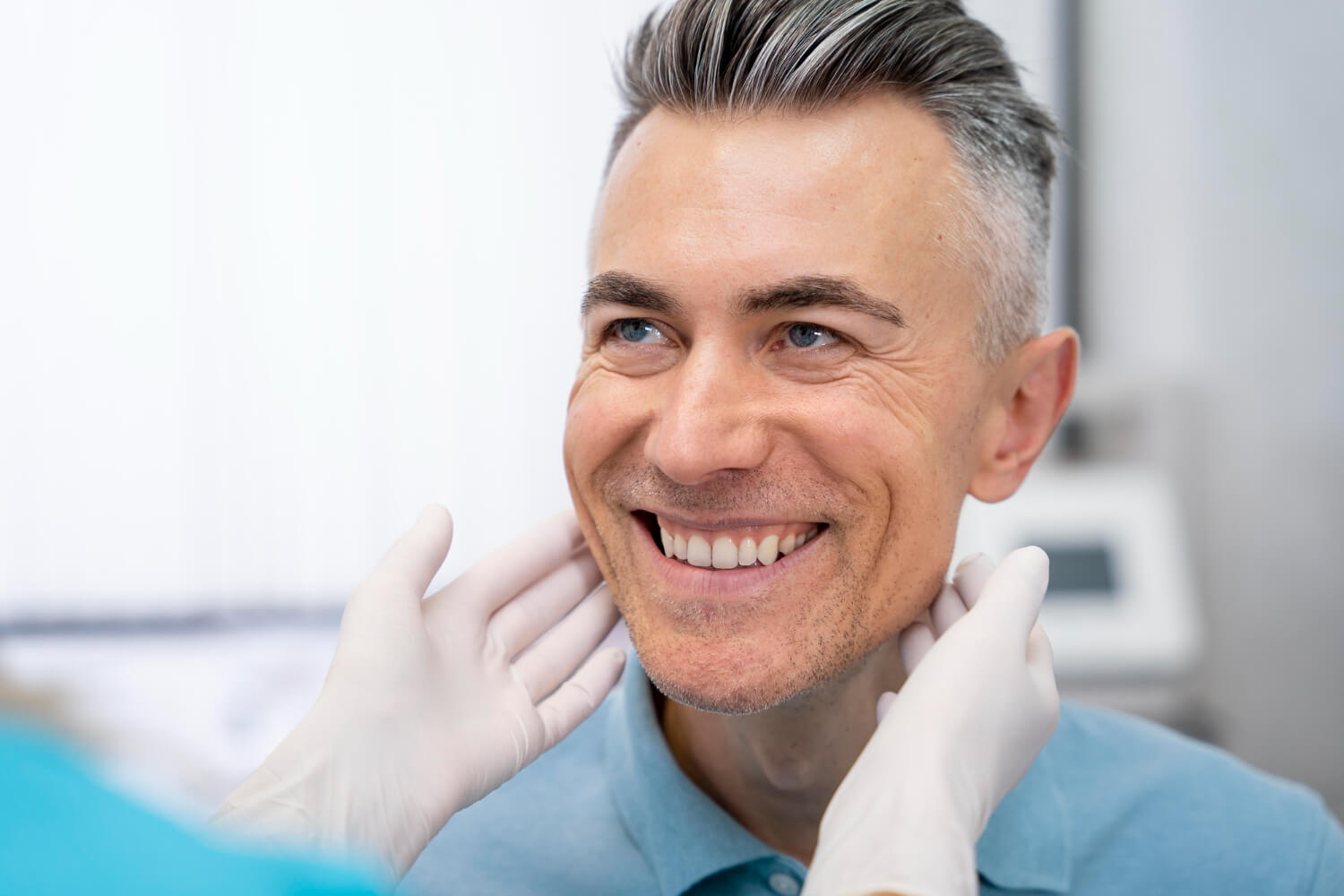 Homem grisalho sorrindo durante avaliação para tratamento de prótese protocolo com dentista na Vila Maracanã.