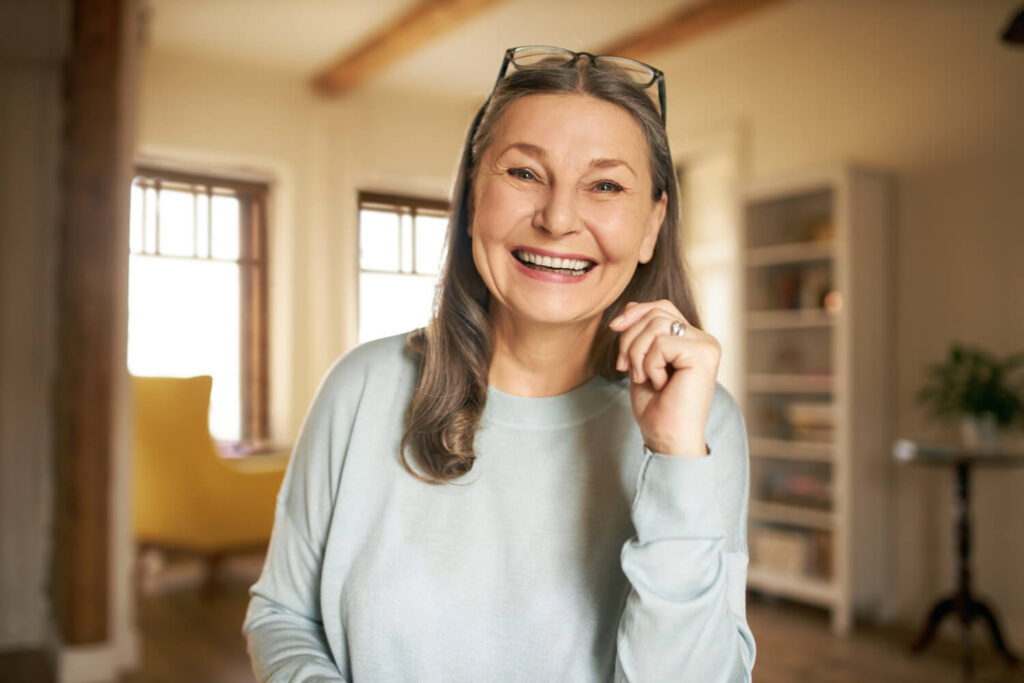Mulher madura sorrindo feliz, destacando reabilitação oral com prótese protocolo no Instituto do Sorriso na Vila Maracanã - SP.